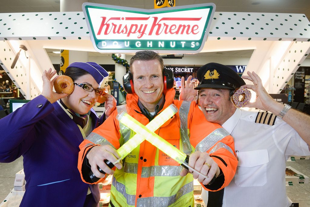 Picture by Nick Ponty  19/11/16 Krispy Kreme opens at Glasgow Airport  Logan Air Cabin Crew manager Avril McEwan and Pilot Eddie Watt try out some doughnuts with Glasgow Airport airside operations officer Derek Paterson (centre).