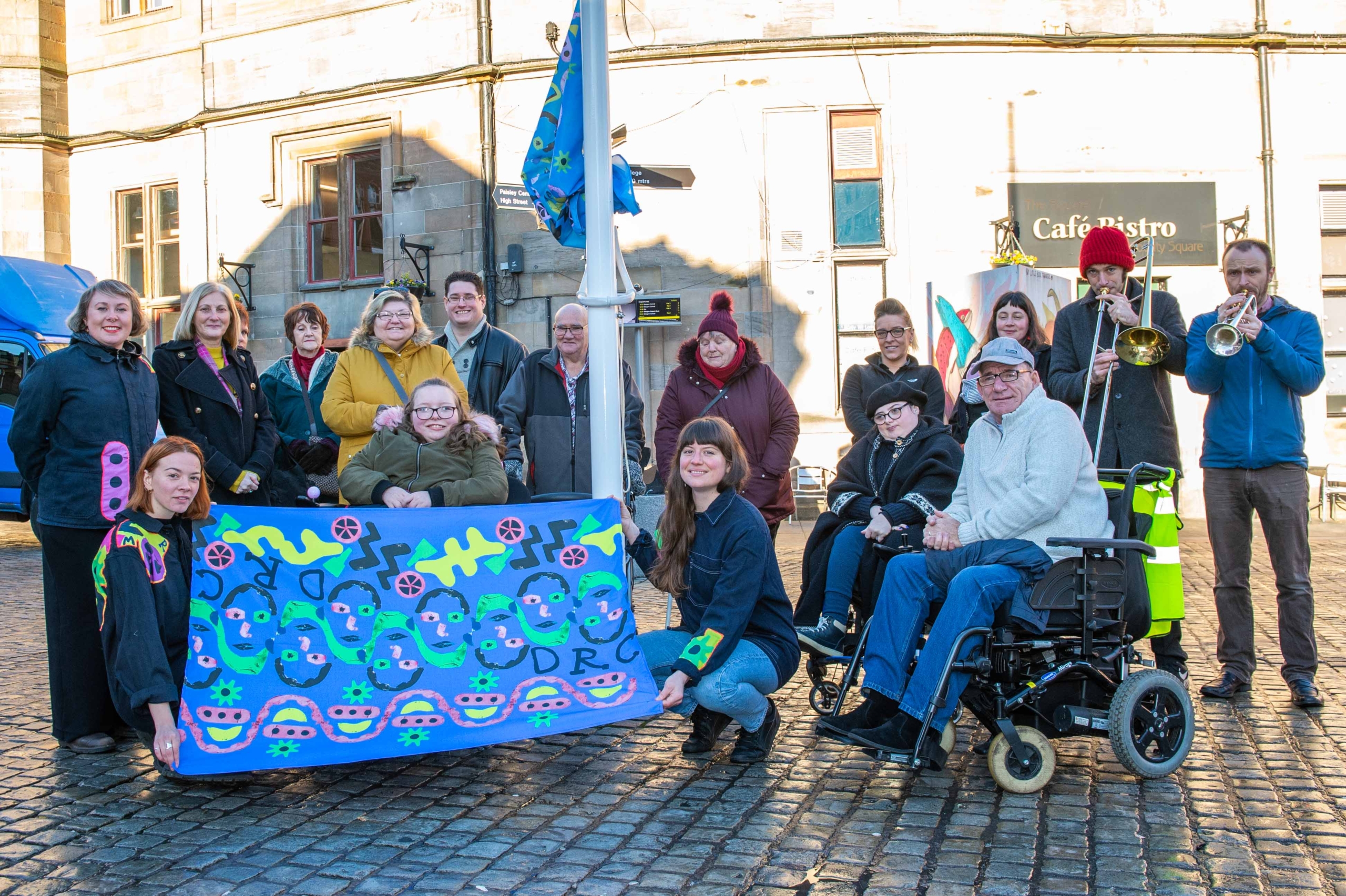 The group from the Disability Resource Centre gathered alongside the artists and musicians from Brass Aye to see the flag raised