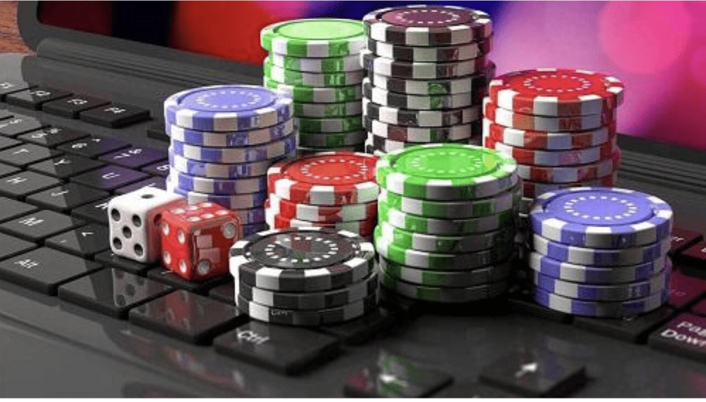 Stacks of colorful poker chips and two dice are arranged on top of a black computer keyboard, suggesting the concept of online gambling or virtual casino games.