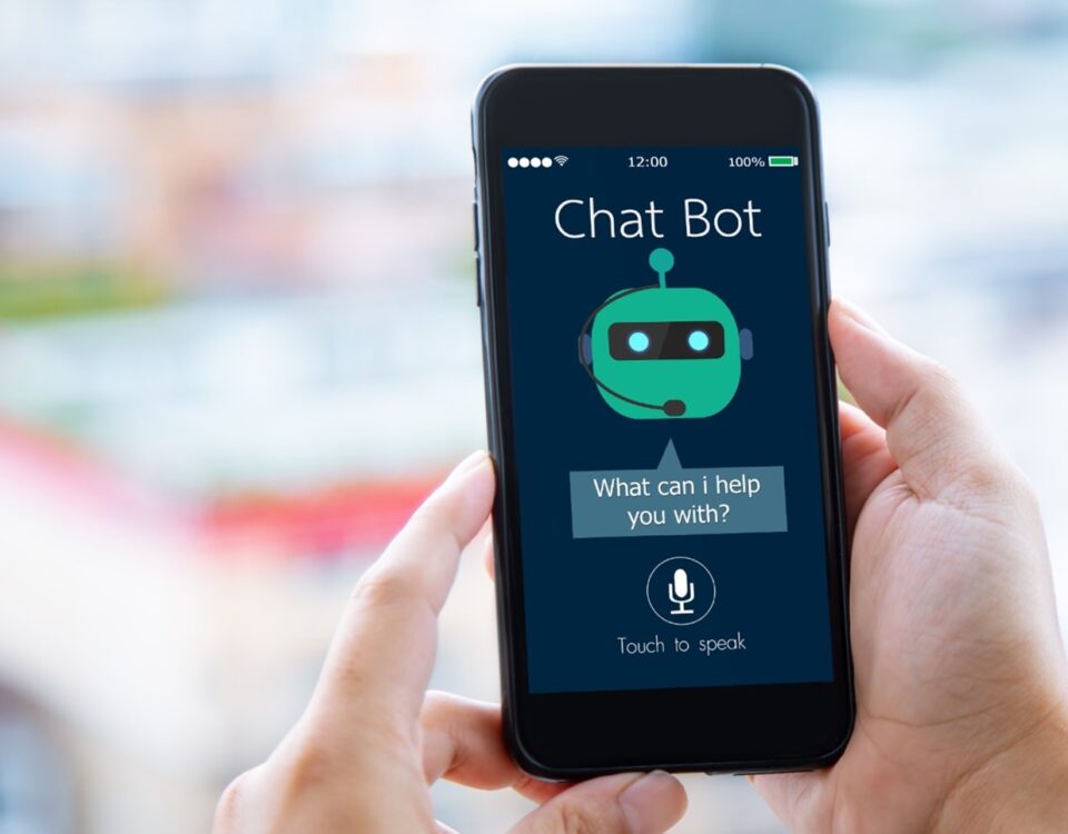A person holds a smartphone displaying a chatbot app interface. The screen shows a green robot icon with the text "What can I help you with?" and a microphone button labeled "Touch to speak." The background is blurred.