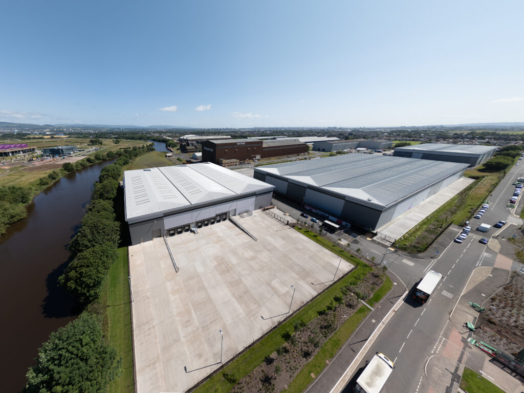 A large warehouse with a river and trees.