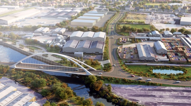Aerial view of a modern arched bridge over a river, surrounded by warehouses, roads, parked cars, trees, and industrial buildings in an urban area.