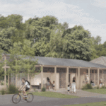 A modern, single-story building with a gabled roof sits in front of tall green trees. People are gathered outside; one person rides a bicycle, and others walk or sit near the entrance. The sky is partly cloudy.