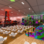 Indoor play center with colorful climbing structures, slides, tunnels, and obstacle courses beside rows of white tables and chairs on a wooden floor, under bright overhead lighting.