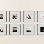 Eight framed black-and-white mountain photographs are arranged in two rows on a plain, light-colored wall. Each frame has a wide white matting, highlighting the small landscape photo in the center.