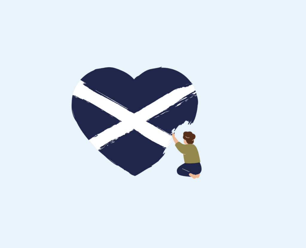A person kneels and paints a large heart-shaped Scottish flag with blue background and white diagonal cross on a light blue background.