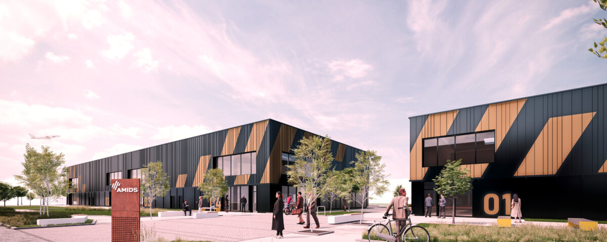 A modern business park with geometric black and gold buildings, people walking and cycling, green landscaping, trees, and a blue sky with wispy clouds. A red sign labeled "MAPIS" stands in the foreground.